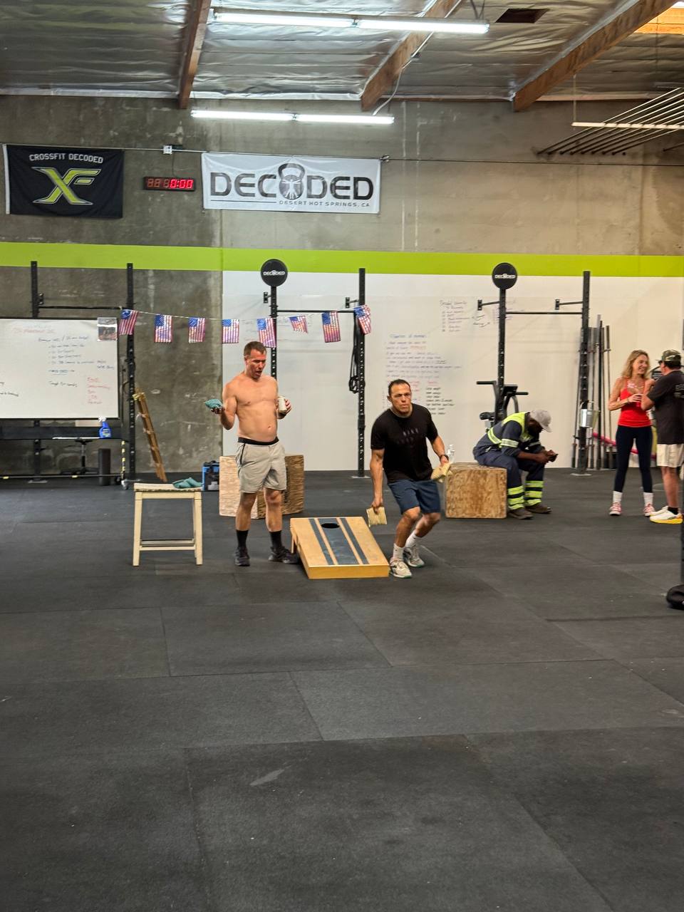 A cornhole game on the gym floor with American flag bunting on the wall