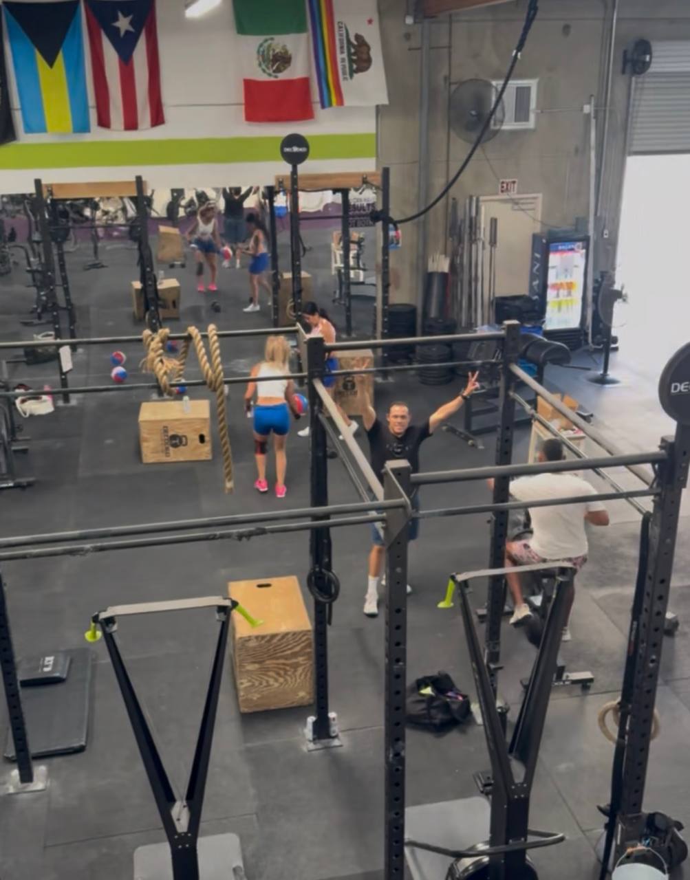 Overhead view of the busy gym floor with a member throwing up a peace sign