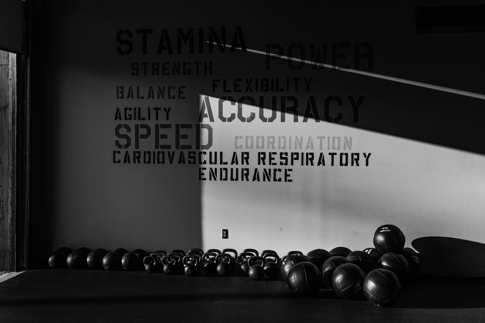 Row of kettlebells and medicine balls against a gym wall